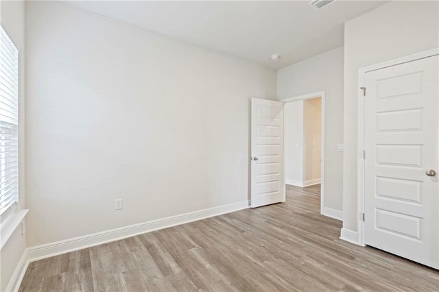 unfurnished bedroom with baseboards, multiple windows, and light wood-style floors