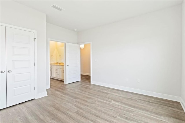 unfurnished bedroom with light wood-style floors, baseboards, visible vents, and a closet