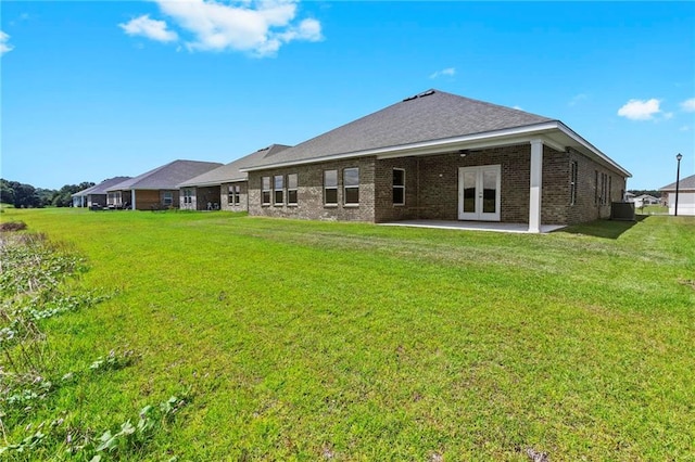 back of property featuring french doors, brick siding, a lawn, and a patio