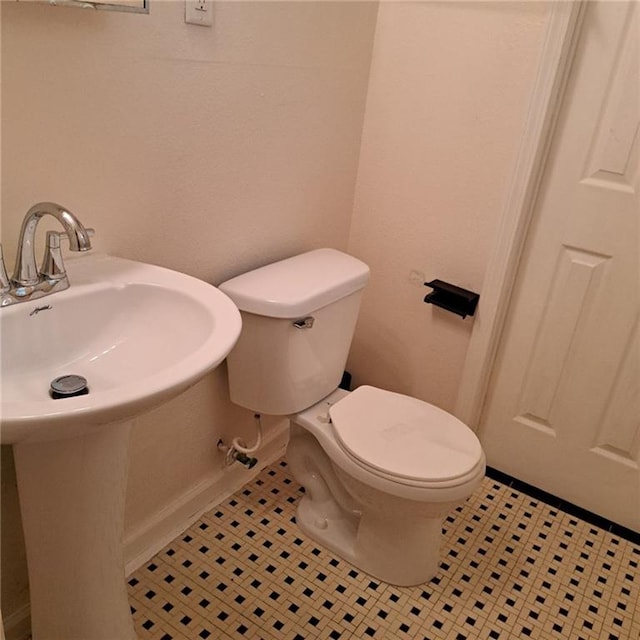 bathroom with toilet, sink, and tile patterned flooring