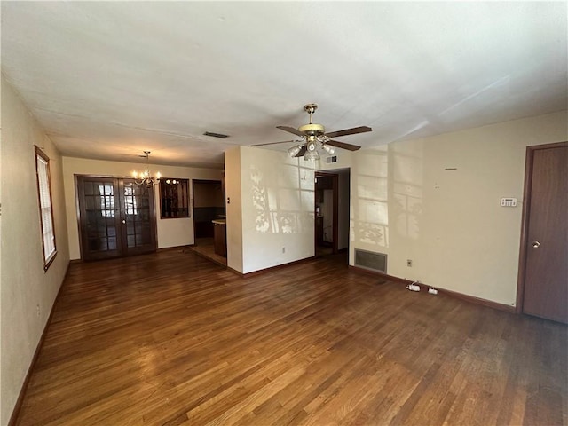 unfurnished living room with dark wood-style flooring, visible vents, baseboards, and ceiling fan with notable chandelier