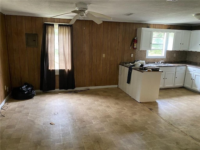 236 Bishop Phillips Ave, Mobile, AL 36608 - kitchen featuring wood walls, white cabinets, ceiling fan, a textured ceiling, and tasteful backsplash