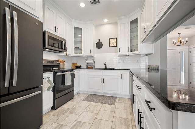 kitchen with visible vents, appliances with stainless steel finishes, a sink, white cabinetry, and backsplash