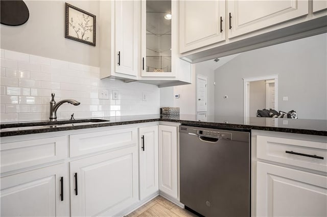 kitchen featuring dark stone counters, a sink, white cabinetry, decorative backsplash, and dishwasher