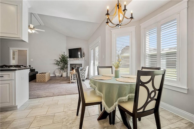 dining room with lofted ceiling, a fireplace, baseboards, and ceiling fan with notable chandelier