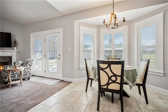 dining space featuring a fireplace, baseboards, and a notable chandelier