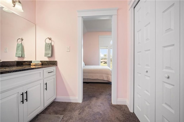 bathroom featuring carpet flooring, connected bathroom, vanity, and baseboards