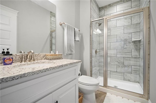 bathroom with vanity, a shower stall, and toilet