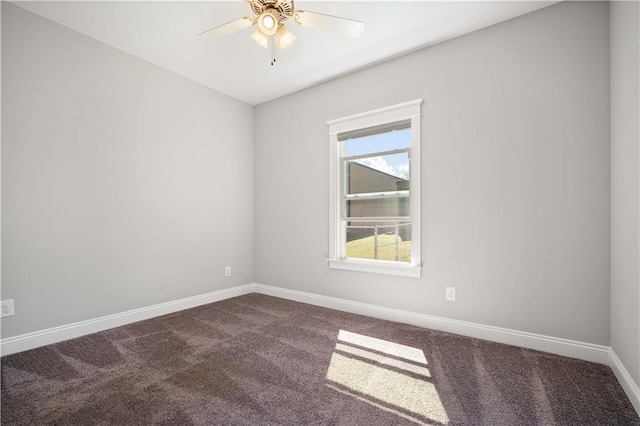 spare room with dark carpet, baseboards, and ceiling fan