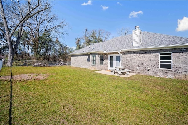 back of property with a fenced backyard, brick siding, a lawn, a chimney, and a patio area