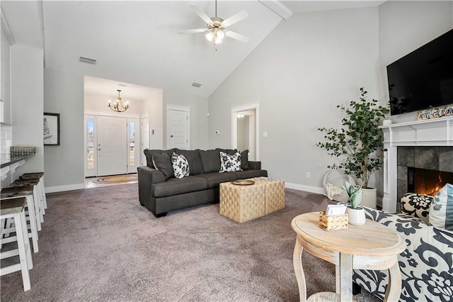 carpeted living area with visible vents, a tiled fireplace, high vaulted ceiling, baseboards, and ceiling fan with notable chandelier