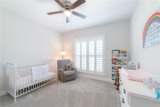 carpeted bedroom featuring ceiling fan and a crib