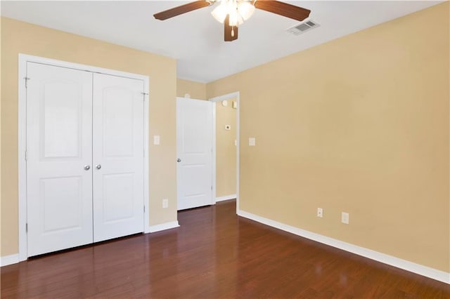 unfurnished bedroom with dark hardwood / wood-style flooring, a closet, and ceiling fan