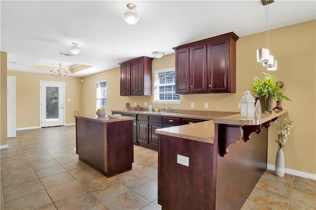 kitchen featuring sink, a breakfast bar, a raised ceiling, decorative light fixtures, and kitchen peninsula