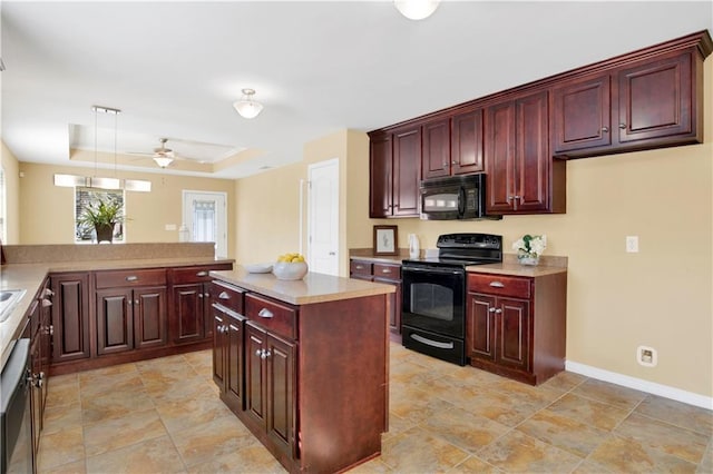 kitchen featuring kitchen peninsula, decorative light fixtures, black appliances, a center island, and a tray ceiling