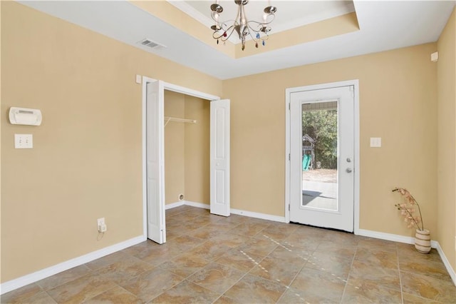 doorway featuring a raised ceiling and an inviting chandelier