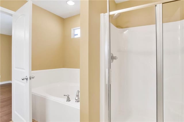 bathroom featuring shower with separate bathtub and wood-type flooring