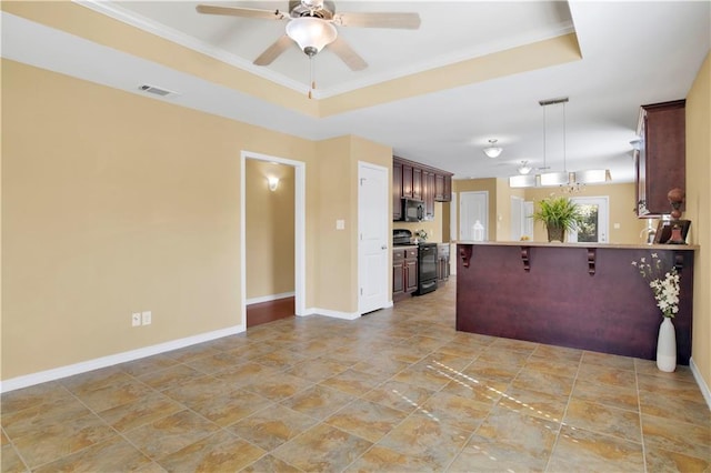 kitchen with a tray ceiling, a kitchen breakfast bar, hanging light fixtures, and black appliances