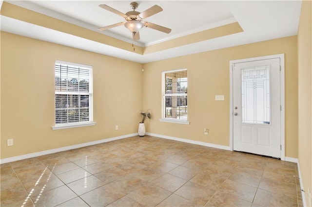 tiled spare room with a wealth of natural light, ornamental molding, a raised ceiling, and ceiling fan