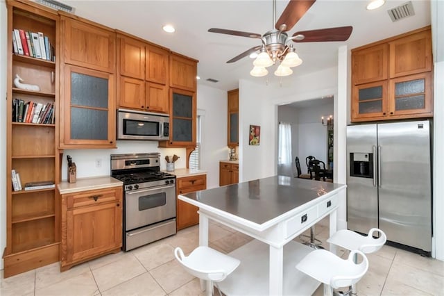 kitchen featuring brown cabinetry, light tile patterned floors, visible vents, and appliances with stainless steel finishes