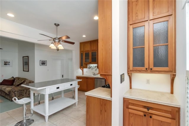 kitchen featuring recessed lighting, open floor plan, light countertops, a ceiling fan, and glass insert cabinets