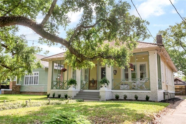 view of front of house with a porch, a chimney, and a front yard