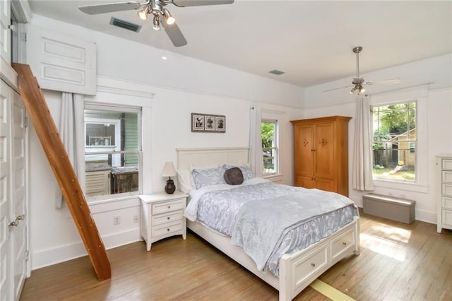 bedroom featuring baseboards, ceiling fan, light wood finished floors, and visible vents