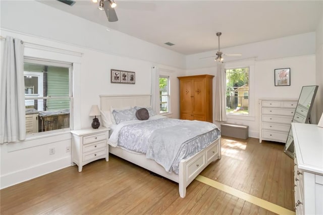 bedroom with baseboards, visible vents, light wood-type flooring, and a ceiling fan
