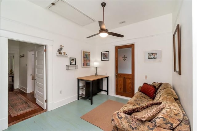 living area featuring a ceiling fan, baseboards, visible vents, and wood finished floors
