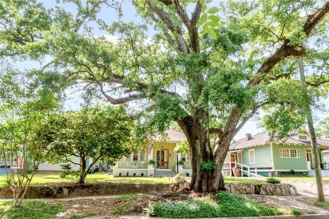 view of property hidden behind natural elements featuring a porch