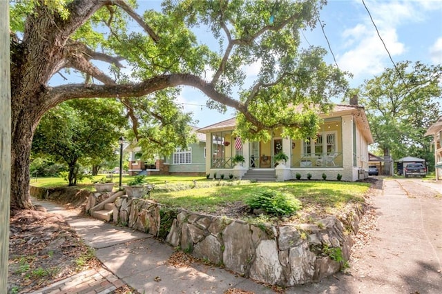 view of front of property featuring a porch, a front lawn, and a chimney