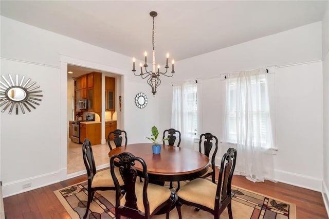 dining area featuring wood finished floors, baseboards, and a notable chandelier