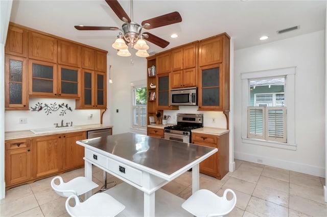 kitchen with visible vents, a sink, open shelves, brown cabinets, and stainless steel appliances