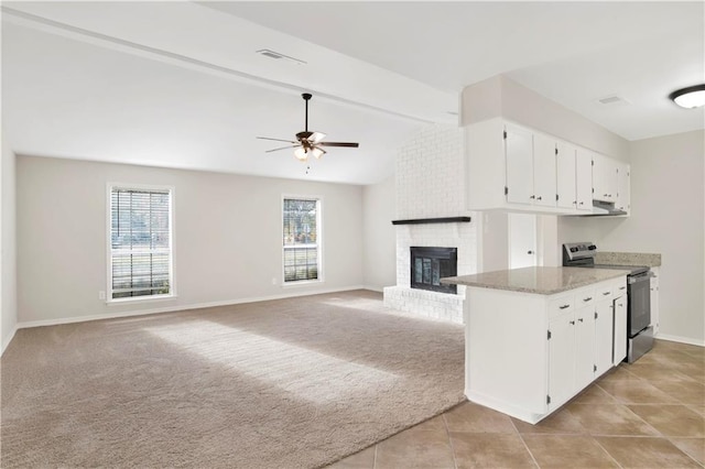 kitchen with electric stove, light stone counters, light carpet, and white cabinets