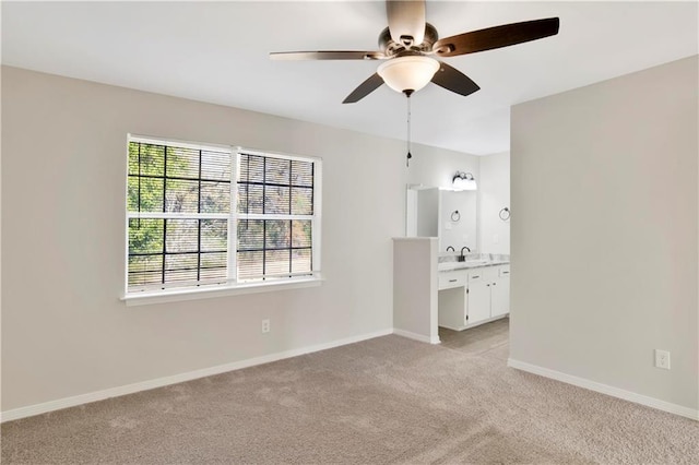 unfurnished bedroom with connected bathroom, sink, light colored carpet, and ceiling fan