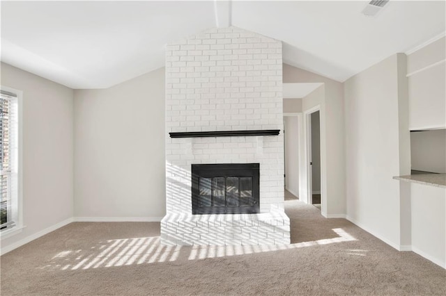 unfurnished living room with lofted ceiling with beams, a brick fireplace, and light colored carpet