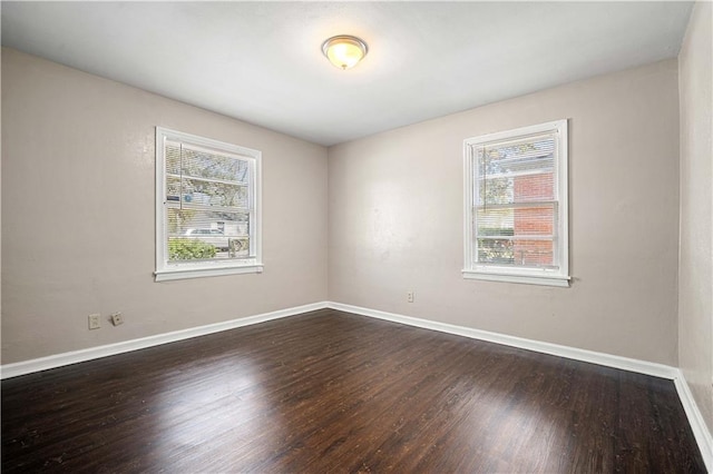 unfurnished room featuring baseboards and dark wood-style floors