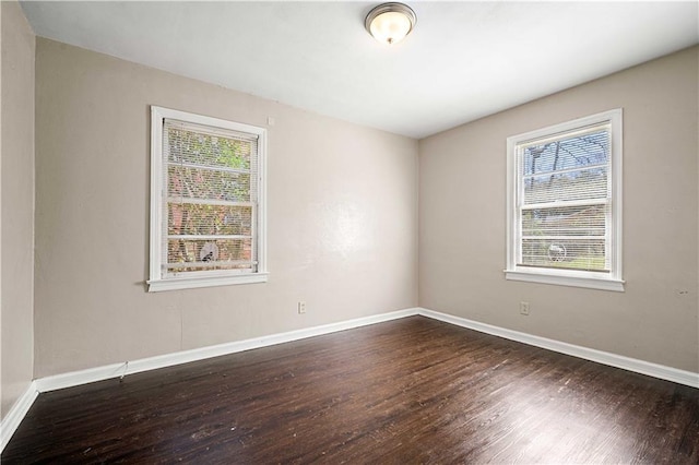 unfurnished room featuring baseboards and dark wood-style flooring