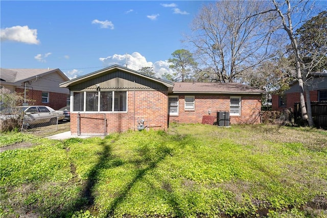 rear view of property with brick siding, central air condition unit, a lawn, and fence