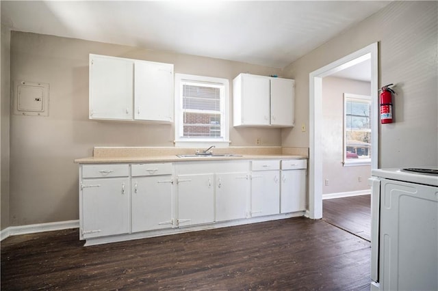 kitchen with dark wood-type flooring, a sink, white cabinets, light countertops, and range