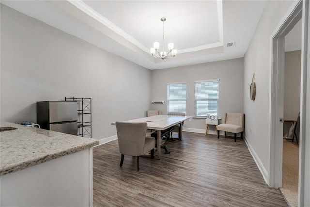 dining space featuring a notable chandelier, a tray ceiling, and dark hardwood / wood-style floors