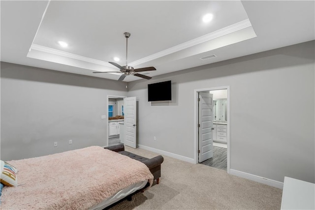 carpeted bedroom featuring ensuite bathroom, ornamental molding, ceiling fan, and a tray ceiling