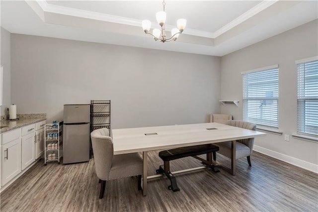 dining space with a raised ceiling, ornamental molding, dark hardwood / wood-style floors, and a chandelier