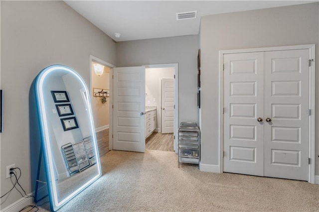 unfurnished bedroom with light carpet, ensuite bath, and a closet