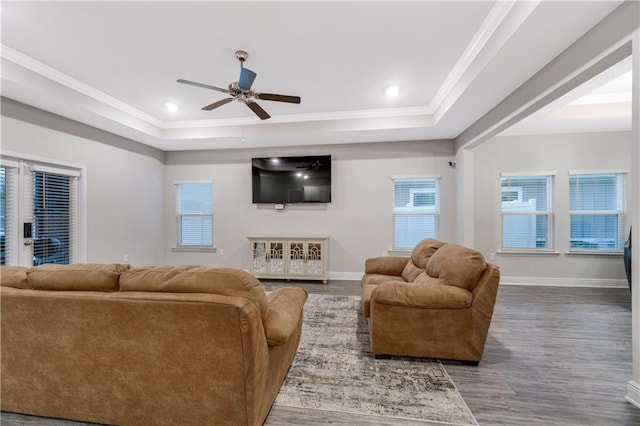 living room featuring hardwood / wood-style flooring, ornamental molding, a raised ceiling, and ceiling fan