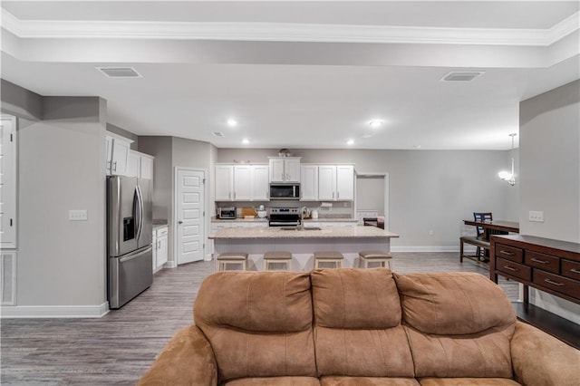 living room featuring ornamental molding, sink, and light wood-type flooring