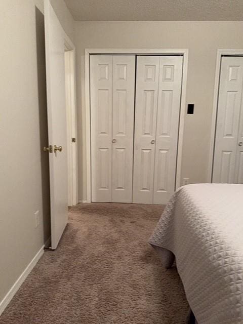 bedroom with carpet floors, baseboards, and a textured ceiling