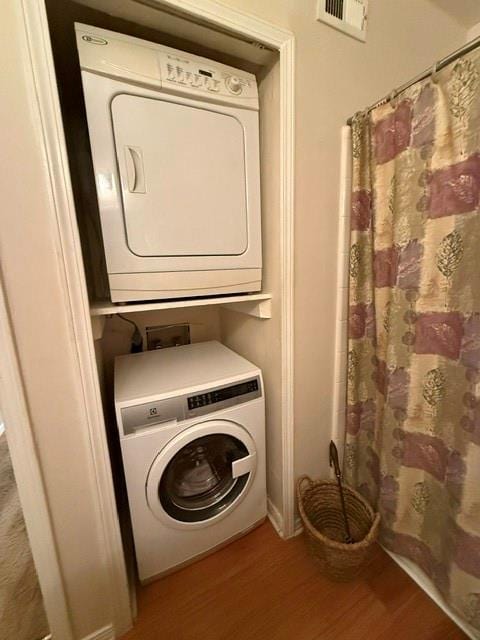 laundry area with visible vents, laundry area, wood finished floors, and stacked washer and clothes dryer