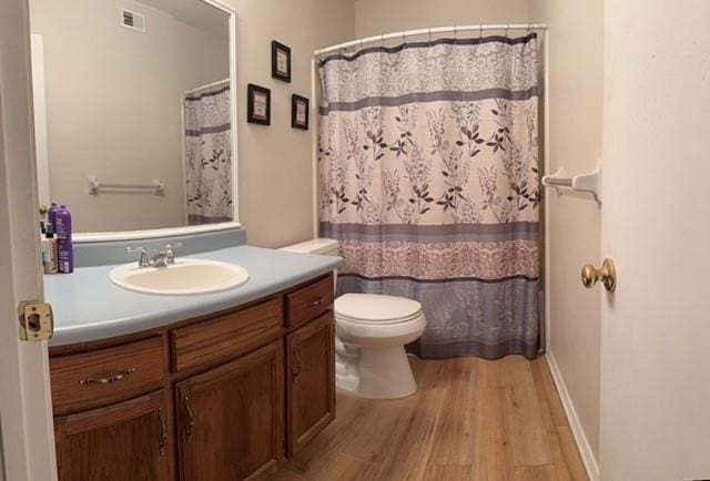 bathroom featuring baseboards, visible vents, toilet, wood finished floors, and vanity