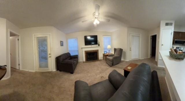 living room featuring visible vents, carpet, a fireplace, and a ceiling fan